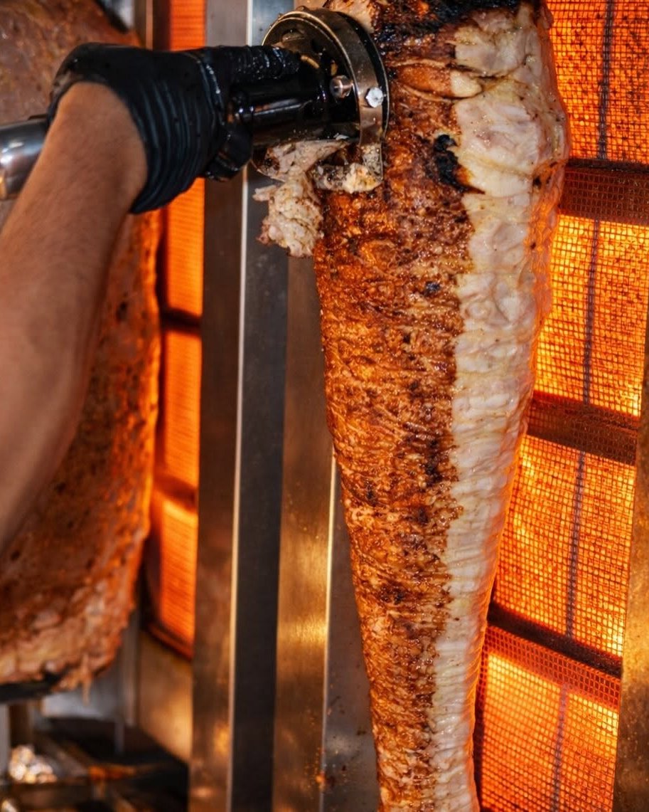 Shawarma affettato dallo spiedo verticale sulla fiamma